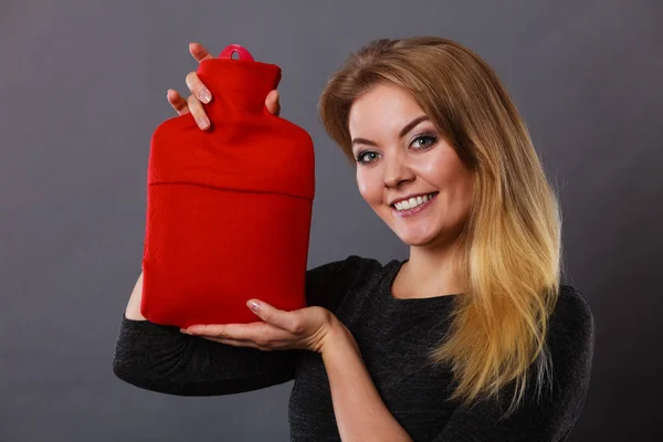 Woman holding warm red hot water bottle — Stock Photo, Image