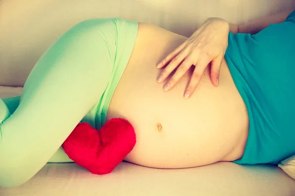 彼女の腹に触れるソファで横になっている妊娠中の女性 — ストック写真