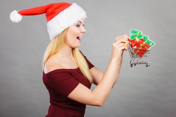 Santa mulher segurando carrinho de compras com presentes de Natal — Fotografia de Stock