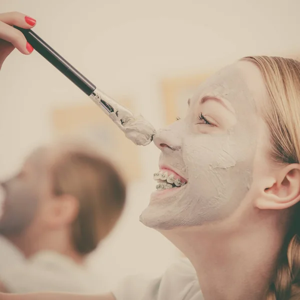 Mutlu genç kadın burnuna çamur maskesi uygulama — Stok fotoğraf