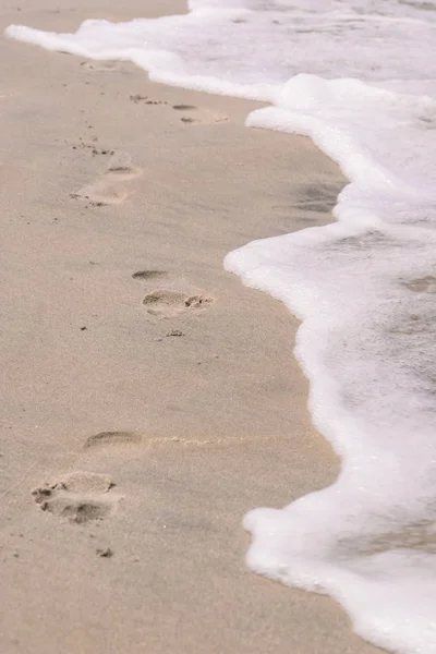 Footsteps on beach near water — Stock Photo, Image