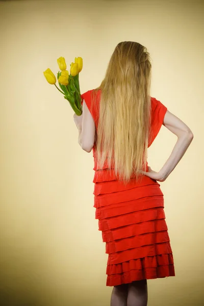 Жінка з жовтими тюльпанами, вид ззаду — стокове фото