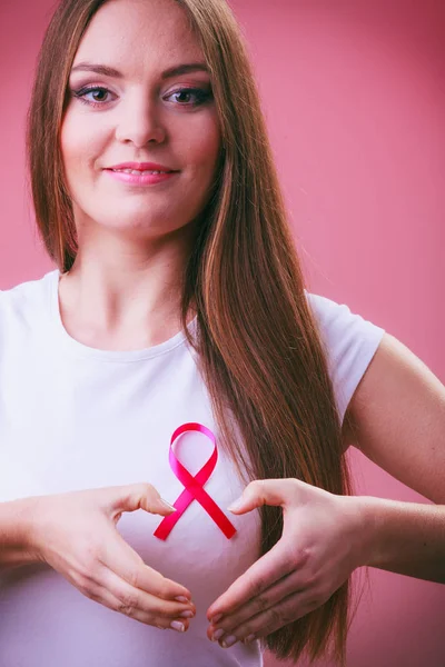 Breast cancer. Woman making heart shape on pink ribbon — Stock Photo, Image
