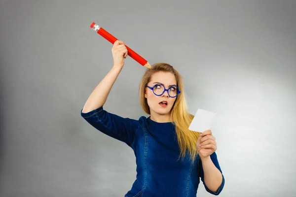 Verwirrte Frau hält großen Bleistift-Zettel in der Hand — Stockfoto