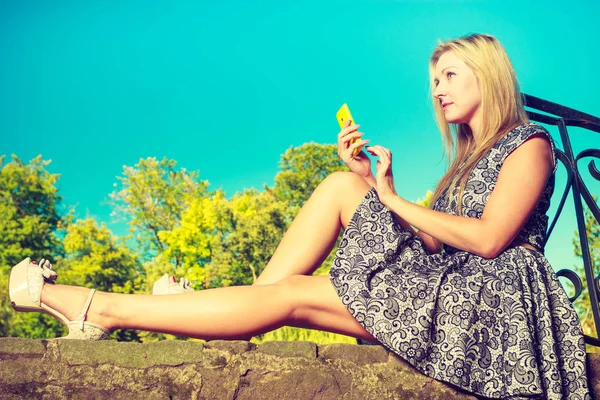 Frau sitzt im Park, entspannt sich und telefoniert — Stockfoto