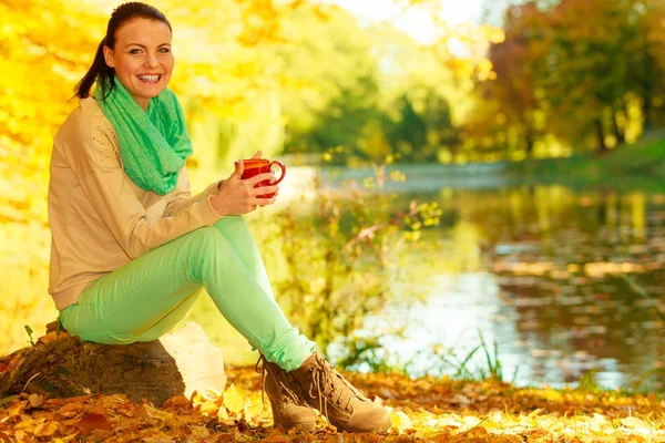 Woman relaxing in park drinking drink from mug — Stock Photo, Image