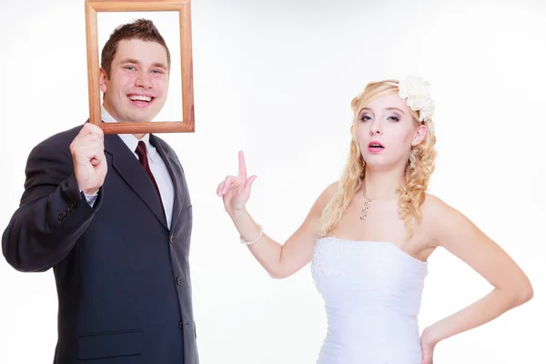Novio y novia sosteniendo marco vacío — Foto de Stock