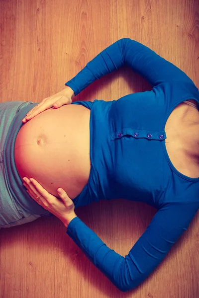 Femeie întinsă pe podea arătând burta însărcinată — Fotografie, imagine de stoc