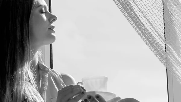 Nő keres ablakon, kellemes kávé, tea — Stock Fotó