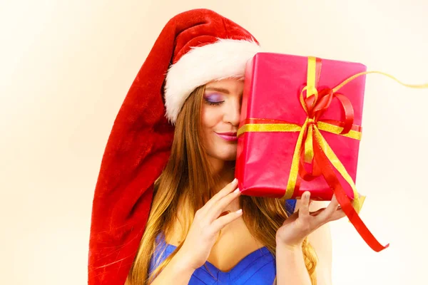 在圣诞老人的帽子的女人抱着礼品盒。圣诞节的时候 — 图库照片