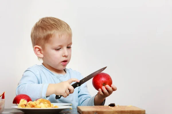 Kleiner Junge schält Äpfel mit Messer und isst — Stockfoto