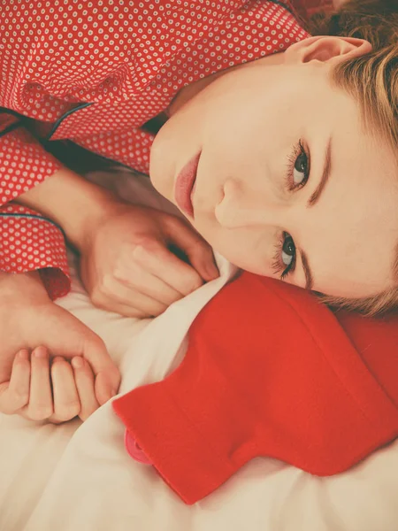 Woman sleeping with warm red hot water bottle — Stock Photo, Image