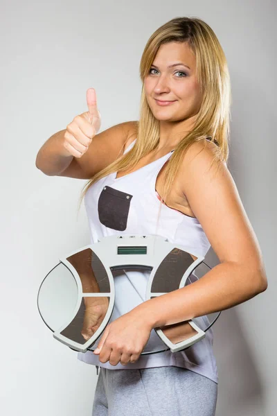 Happy woman holding weight machine showing thumb up — Stock Photo, Image