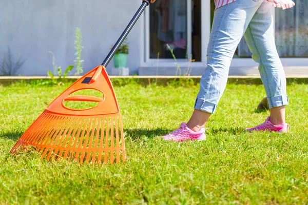 Kobieta za pomocą prowizji do czyszczenia trawnika ogrodowego — Zdjęcie stockowe