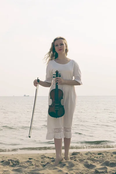 Mulher na praia perto do mar segurando violino — Fotografia de Stock