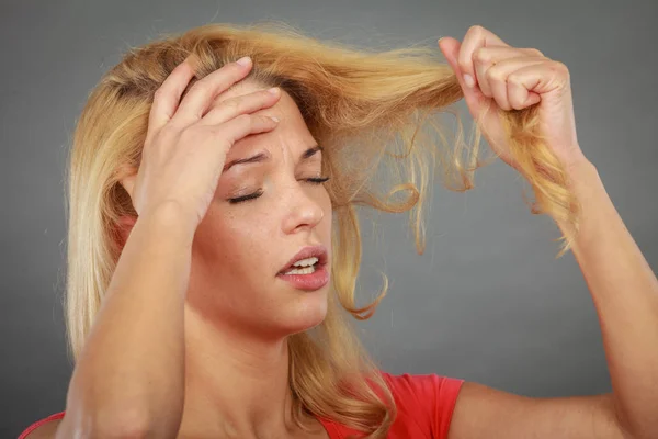 Donna triste guardando le estremità dei capelli danneggiati — Foto Stock