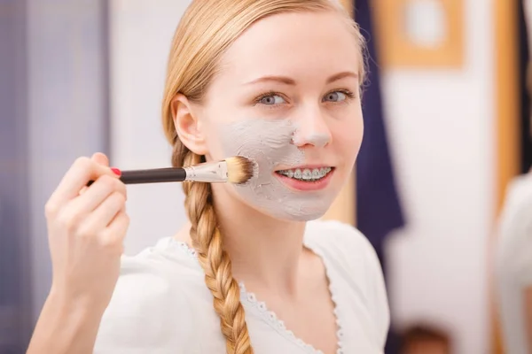 Ευτυχισμένη γυναίκα εφαρμόζοντας λάσπη μάσκα στο πρόσωπό — Φωτογραφία Αρχείου
