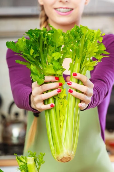 Женщина на кухне держит зеленый сельдерей — стоковое фото