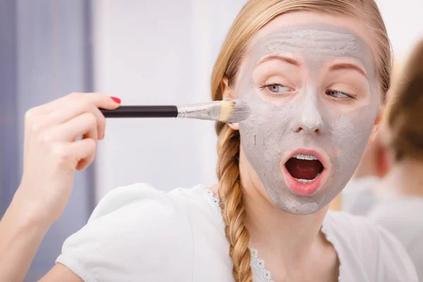 Femme appliquant avec un masque de boue d'argile brosse sur son visage — Photo