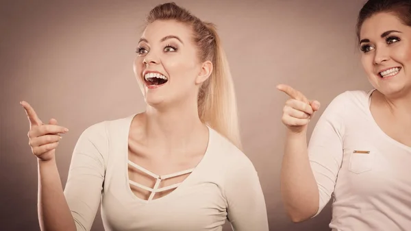 Mulheres felizes apontando para cima com um dedo . — Fotografia de Stock