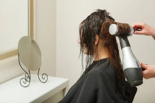 Hairdresser styling woman dark long hair — Stock Photo, Image