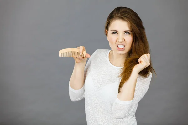 Mujer enojada tratando de cepillarse el pelo —  Fotos de Stock