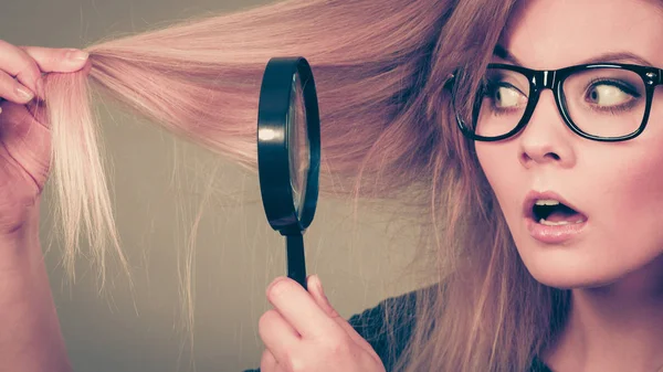 Woman holding magnifying glass looking at hair — Stock Photo, Image