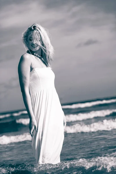 Блондинка в платье ходит в воде — стоковое фото