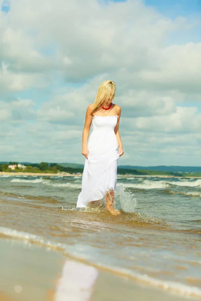 Mulher loira vestindo vestido andando na água — Fotografia de Stock