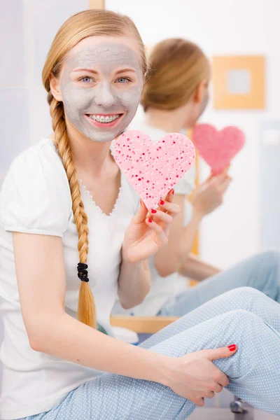 Mulher com máscara cinza segurando esponja do coração — Fotografia de Stock