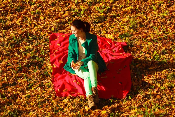 Γυναίκα που κάθεται πάνω στα φθινοπωρινά φύλλα — Φωτογραφία Αρχείου