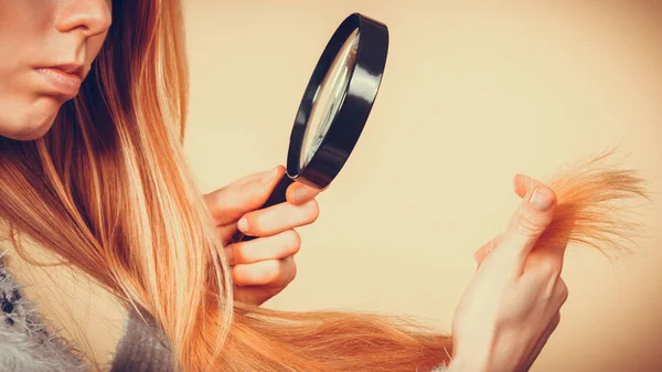 Traurige Frau blickt auf beschädigte Haarspitzen. — Stockfoto