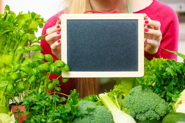 Kvinna med gröna grönsaker håller styrelsen — Stockfoto
