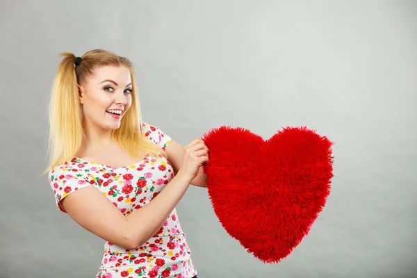 Mujer feliz sosteniendo almohada en forma de corazón — Foto de Stock