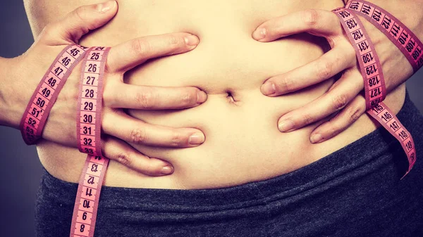 Kvinna som vidrör magen innehav måttband — Stockfoto
