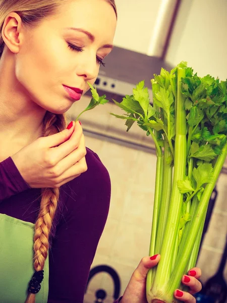 Mulher na cozinha detém aipo verde — Fotografia de Stock