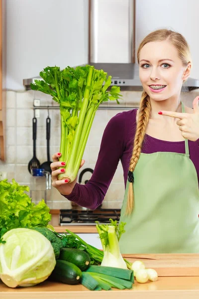 Donna in cucina tiene sedano verde — Foto Stock
