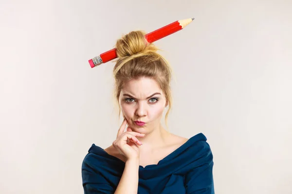 Thinking blonde woman having big pencil in hair — Stock Photo, Image