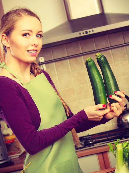 台所で女性はズッキーニの野菜を保持します。 — ストック写真