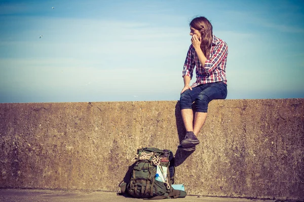 Mann touristischer Backpacker sitzt auf Grunge-Wand im Freien — Stockfoto