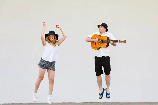 Мужчина с гитарой и женщина прыгает — стоковое фото