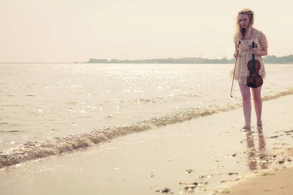 Kobieta na plaży, w pobliżu morza gospodarstwa skrzypce — Zdjęcie stockowe