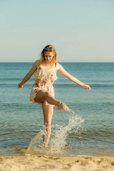 Mulher vestindo vestido brincando com a água no mar — Fotografia de Stock