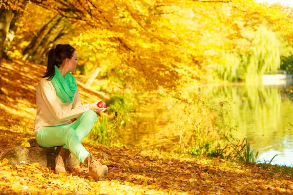 Mujer relajándose en parque sosteniendo fruta de manzana — Foto de Stock