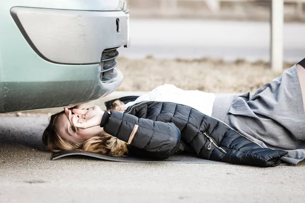 Vrouw, repareren gebroken auto liggen onder het — Stockfoto