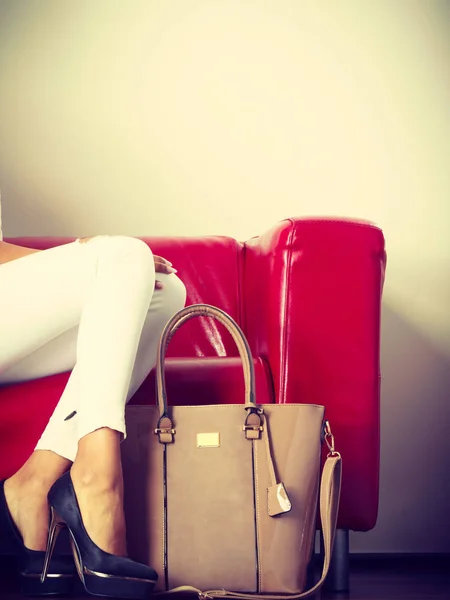 Kvinna sitter på soffan presentera läderväska — Stockfoto