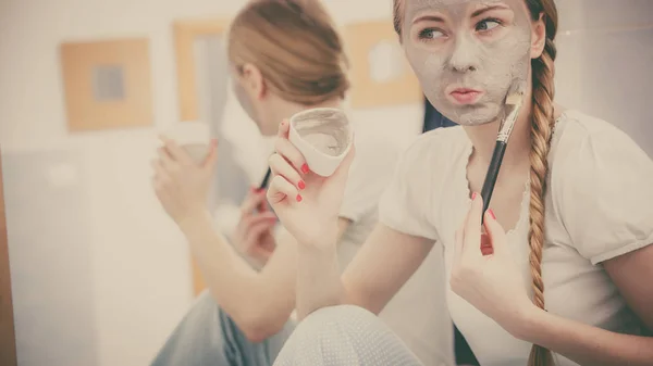 Happy young woman applying mud mask on face — Stock Photo, Image