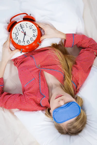 Schlafende Frau im Schlafanzug hält Uhr — Stockfoto