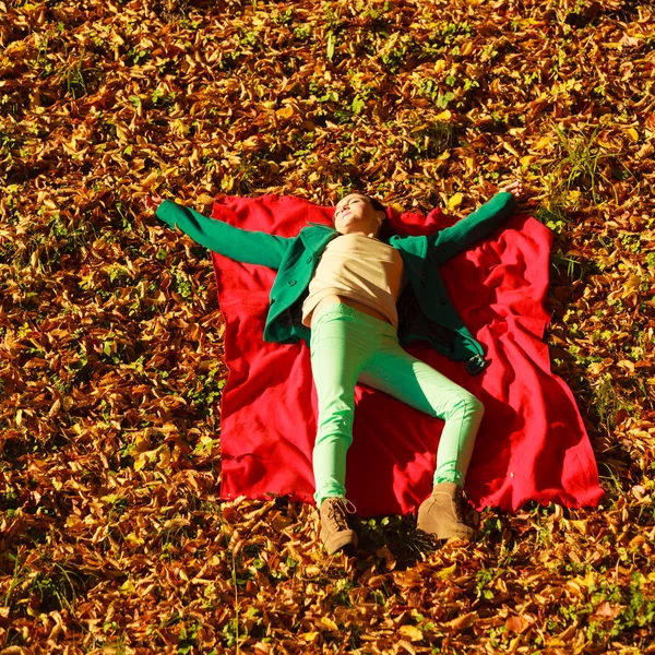Sonbahar yaprakları üzerine oturan kadın — Stok fotoğraf