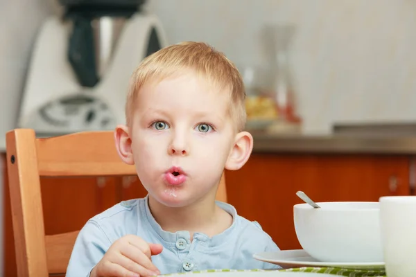 Kid boy eating breakfast, cereals and milk in bowl — Stock Photo, Image